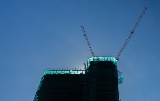 Cranes in operation over a construction site with clear blue skies in Vietnam.