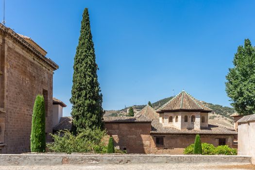 Tree along the pointed rooftop ancient ruins at Alhambra in Granada, Spain, Europe on a bright summer day