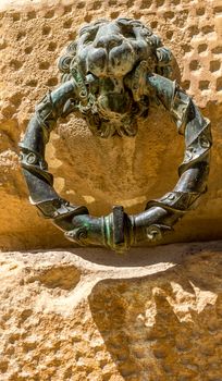 Bronze ring with a lion head figure on the exterior wall of Charles V Palace at Alhambra Palace complex in Granada, Andalusia, Spain, Europe on a bright summer day