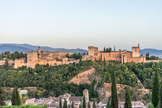 The magnificient Alhambra of Granada, Spain. Alhambra fortress at sunset viewed from Mirador de San Nicolas during evening twilight hour.