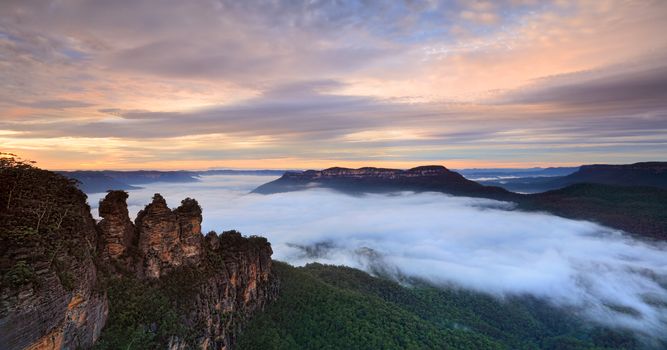 Fog filled Jamison Valley resembles a fluffy white water stream. Warm light from the sky bathes the landscape in a soft muted light and interesting clouds hand overhead.