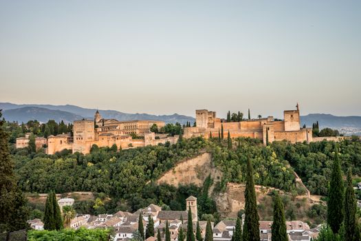 The magnificient Alhambra of Granada, Spain. Alhambra fortress at sunset viewed from Mirador de San Nicolas during evening twilight hour.