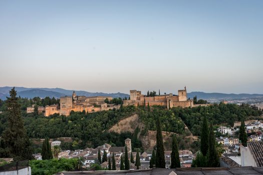 The magnificient Alhambra of Granada, Spain. Alhambra fortress at sunset viewed from Mirador de San Nicolas during evening twilight hour.