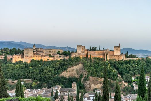 The magnificient Alhambra of Granada, Spain. Alhambra fortress at sunset viewed from Mirador de San Nicolas during evening twilight hour.