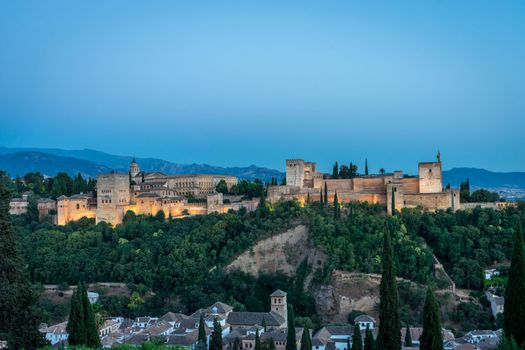 The magnificient Alhambra of Granada, Spain. Alhambra fortress at sunset viewed from Mirador de San Nicolas during evening twilight hour.