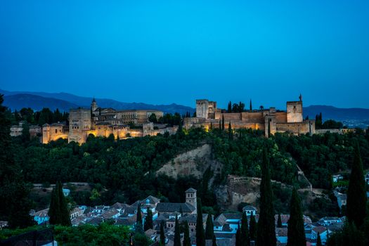 The magnificient Alhambra of Granada, Spain. Alhambra fortress at sunset viewed from Mirador de San Nicolas during evening twilight hour.