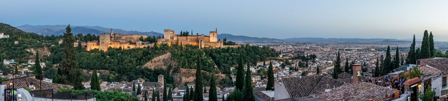 Panorama of the magnificient Alhambra of Granada, Spain. Alhambra fortress at sunset viewed from Mirador de San Nicolas during evening twilight hour.