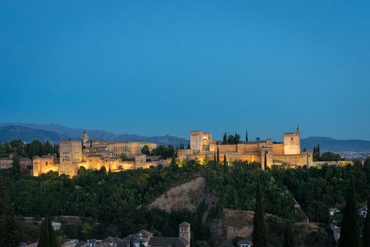 The magnificient Alhambra of Granada, Spain. Alhambra fortress at sunset viewed from Mirador de San Nicolas during evening twilight hour.