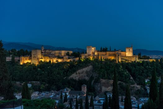 The magnificient Alhambra of Granada, Spain. Alhambra fortress at sunset viewed from Mirador de San Nicolas during evening twilight hour.