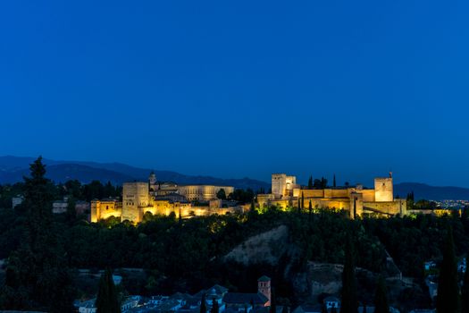 The magnificient Alhambra of Granada, Spain. Alhambra fortress at sunset viewed from Mirador de San Nicolas during evening twilight hour.