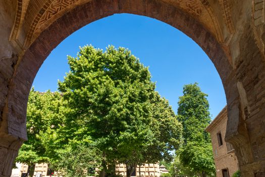 Tree viewed through an Arch at the Alhambra Palace in Granada, Spain, Europe on a bright sunny day with blue sky