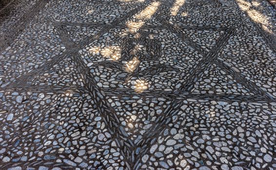 Star pattern with a rose on a stone walking path at the Alhambra palace in Granada, Spain, Europe on a bright summer day