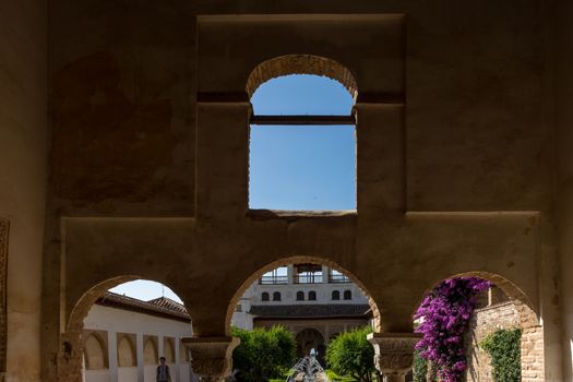 View of The Generalife courtyard, with its famous fountain and garden through an arch. Alhambra de Granada complex at Granada, Spain, Europe on a bright summer day