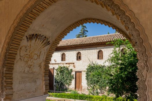 View of The Generalife courtyard, with its famous fountain and garden through an arch. Alhambra de Granada complex at Granada, Spain, Europe on a bright summer day