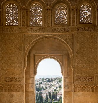 View of the Albayzin district of Granada, Spain, from an arched window in the Alhambra palace near sunset at Granada, Spain, Europe on a bright sunny day