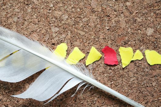 Lot of color paper scraps in a row and feather on wooden background