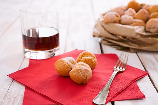 Castagnole, typical Italian carnival sweet on a red napkin and a glass of liqueur