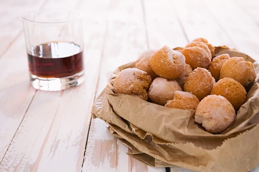 Castagnole, typical Italian carnival sweet in a paper bag and liqueur glass