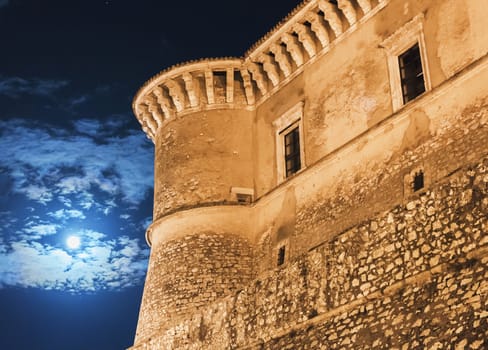 night view of the Alviano medieval castle in Italy with clouds and glowing moon