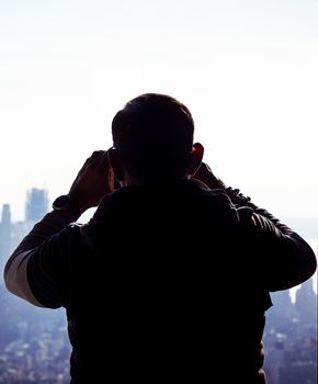 silhouette of a tourist taking photos of an urban landscape with his smartphone