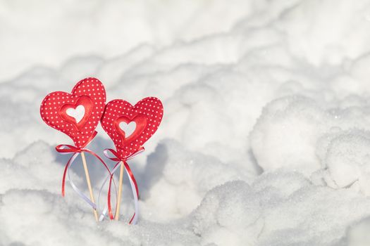 Beautiful valentine holiday background with two checkered hearts on cane, white snow surface.