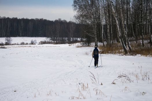 Woman cross country skiing in Russian forest. Active recreation in nature.