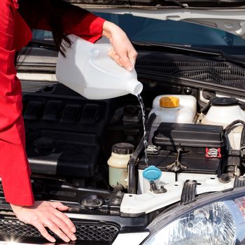 Cropped image of woman pouring windshield washer fluid into car