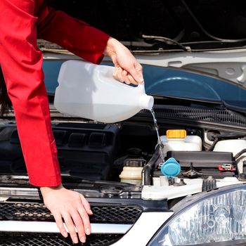 Cropped image of woman pouring windshield washer fluid into car