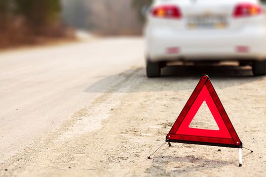 Red triangle sign and automobile on the road, shallow depth of view