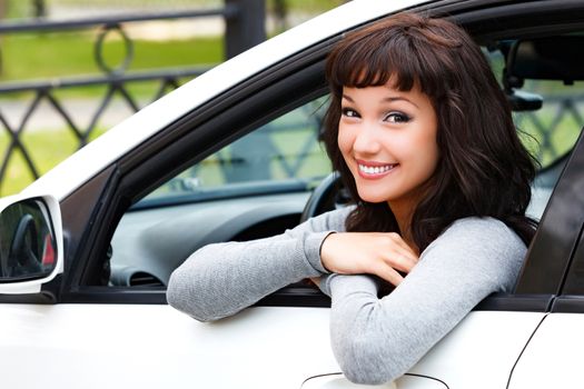 Pretty woman driver smiling to you from the white car