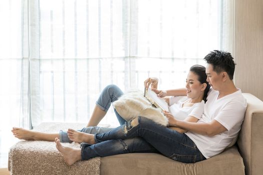 Young Couples reading book tohether in living room of contemporary house for lifestyle concept