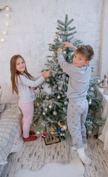 Two children decorating Christmas tree with balls