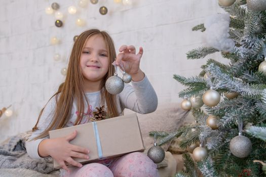Girl under Christmas tree with ball and gift