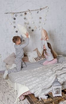 Siblings having pillow fight together on bed at Christmas