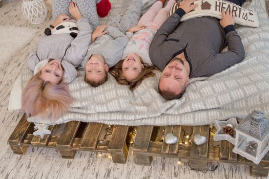Happy family with two children lying on bed faces up