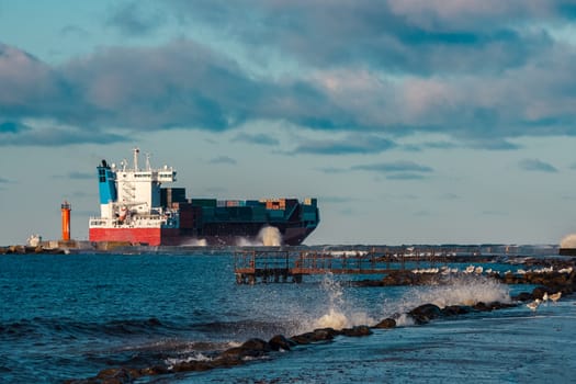 Full red container ship moving in stormy weather