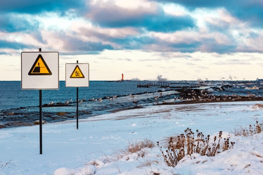 Two yellow warning signs on the winter beach