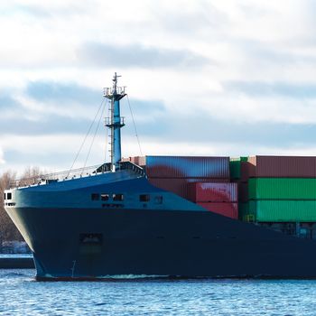 Modern grey container ship moving in still water