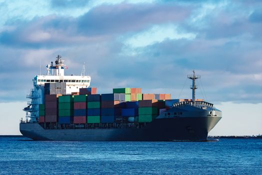 Modern grey container ship moving in still water