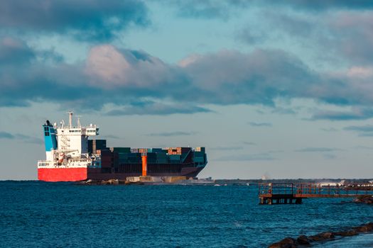Full red container ship moving in still water