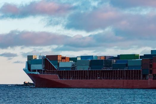 Full red container ship moving in still water