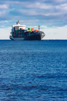 Modern grey container ship moving in still water