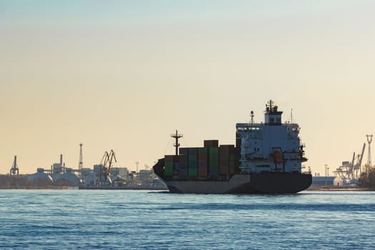 Modern grey container ship moving in still water
