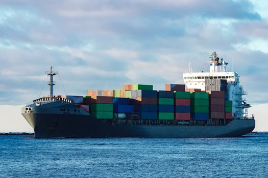 Modern grey container ship moving in still water