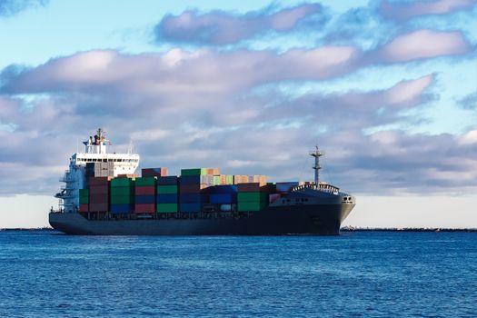 Modern grey container ship moving in still water