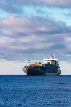 Modern grey container ship moving in still water