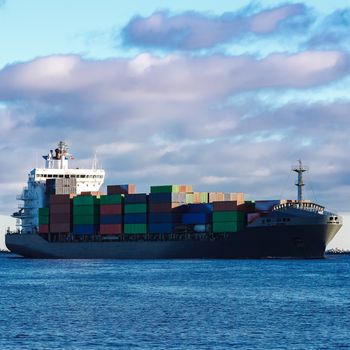 Modern grey container ship moving in still water