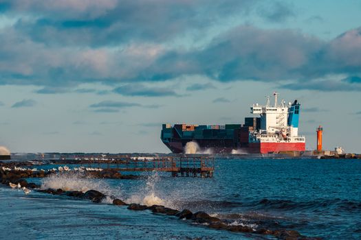Full red container ship moving in stormy weather