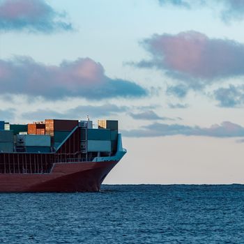 Full red container ship moving in still water