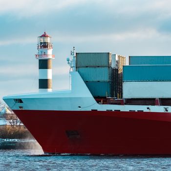 Full red container ship moving in still water